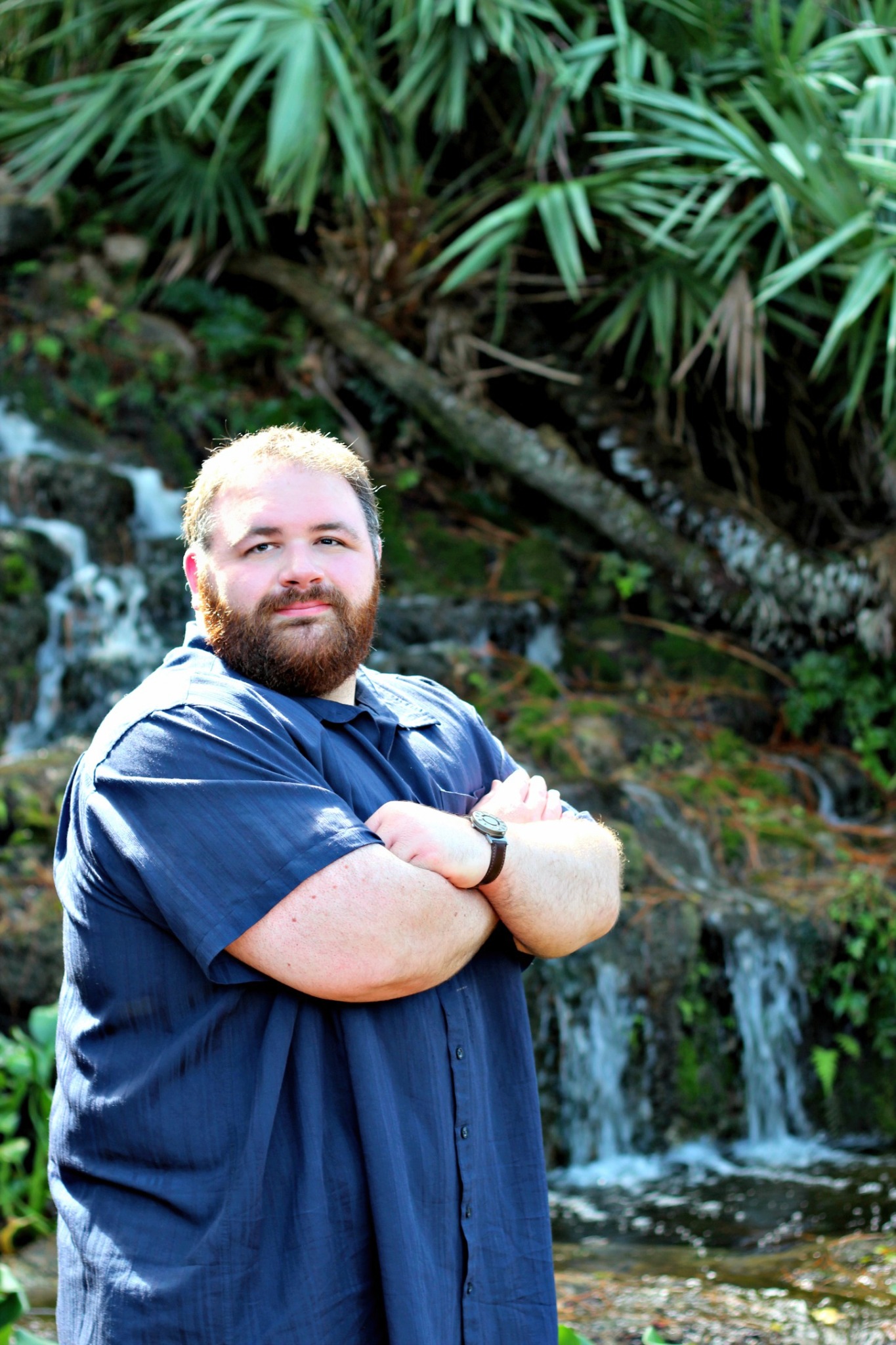 Kevin Lowe standing with his arms crossed in front of a tropical waterfall